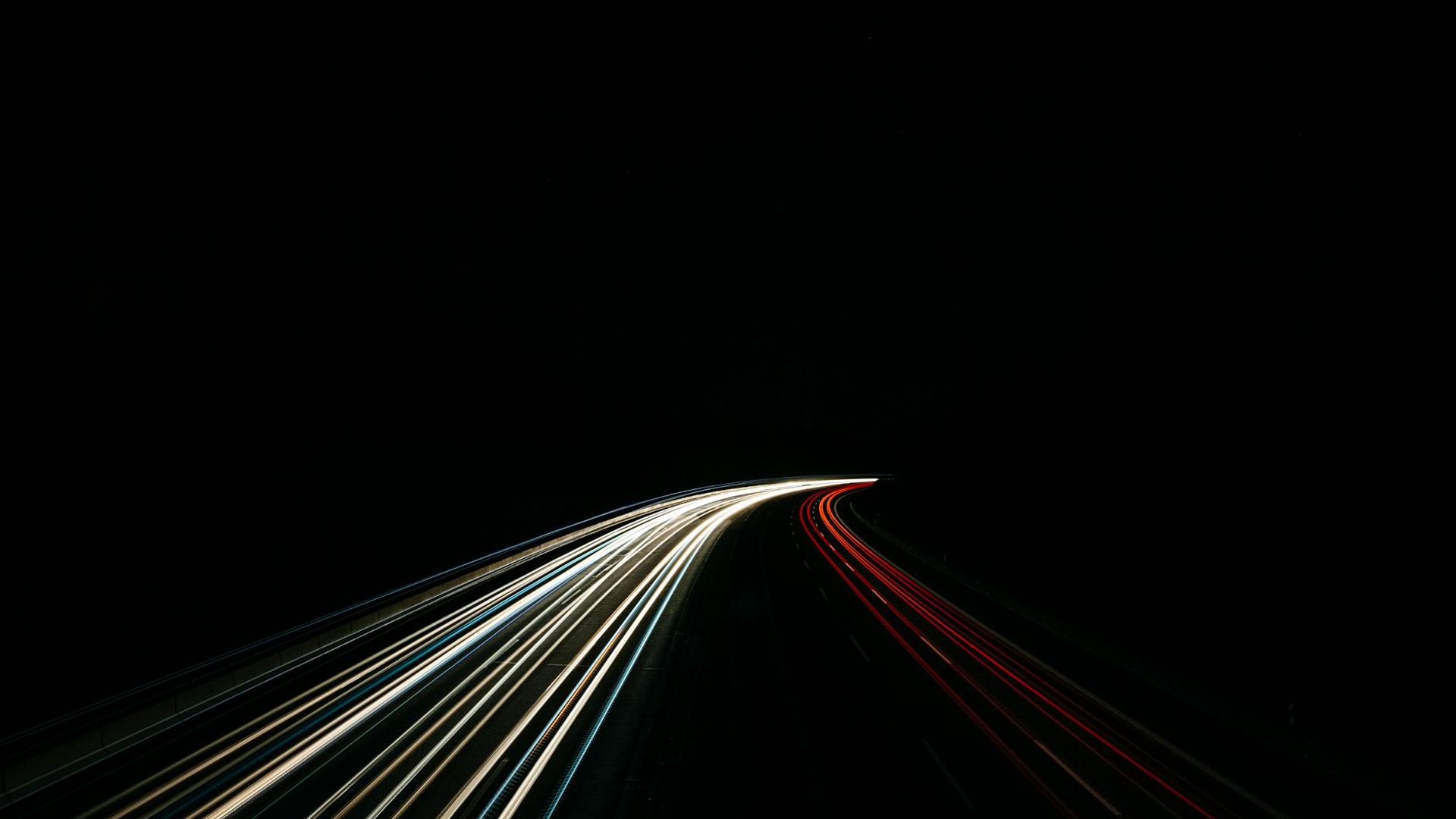 Abstract lilac light trails on a dark carbon background.